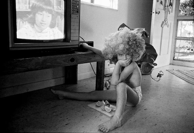 A child sits, snack in hand, captivated by the television—a time when screens were fewer, and imagination had space to breathe between static and storytelling